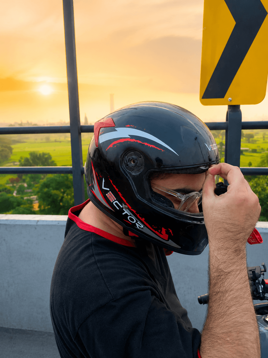 Rider adjusting Vector Red Lightning helmet visor at sunset